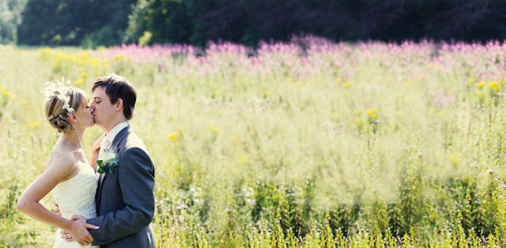 wedding photograph of a bride and groom kissing in a wild flower field