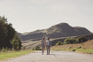 couple walking along a path with hills in the background