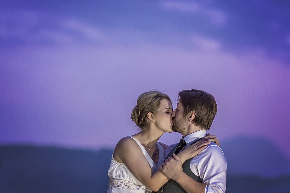 bride and groom kissing against indigo sky wearing wedding dress