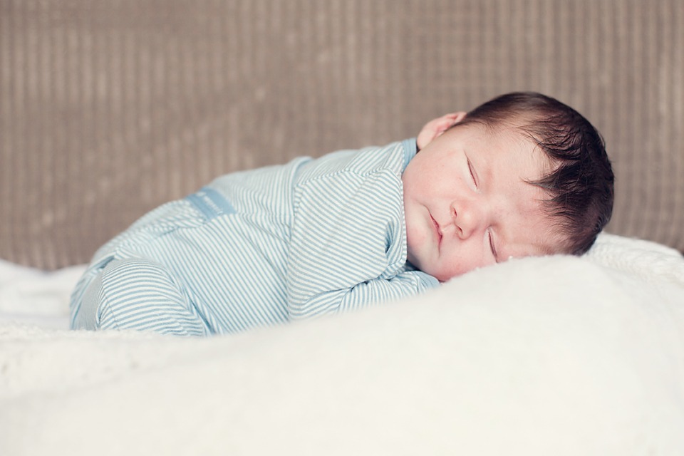 newborn baby sleeping in a blue romper