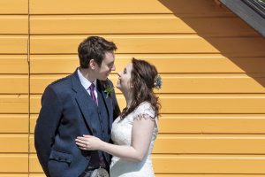 wedding couple against a yellow wall
