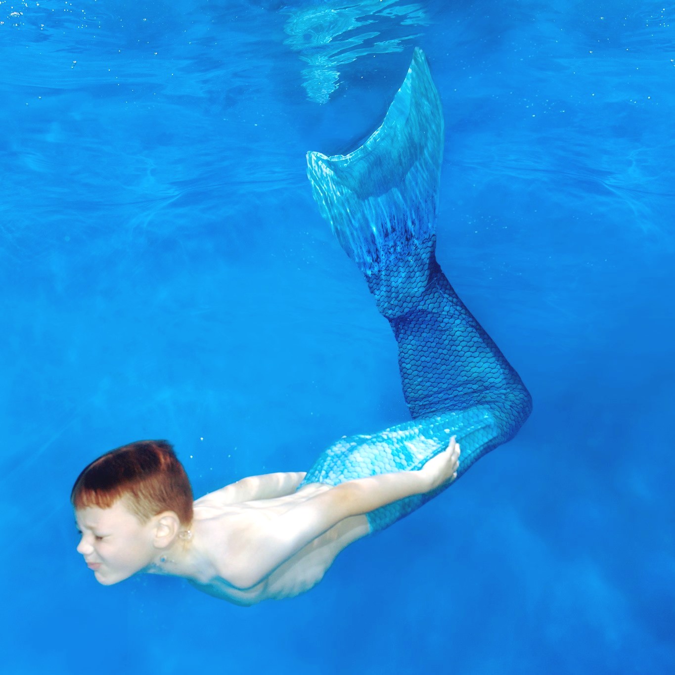 boy with merman tail swimming underwater
