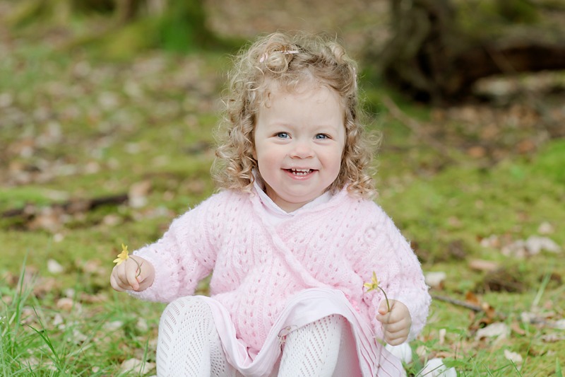 little girl smiling sitting in the woods