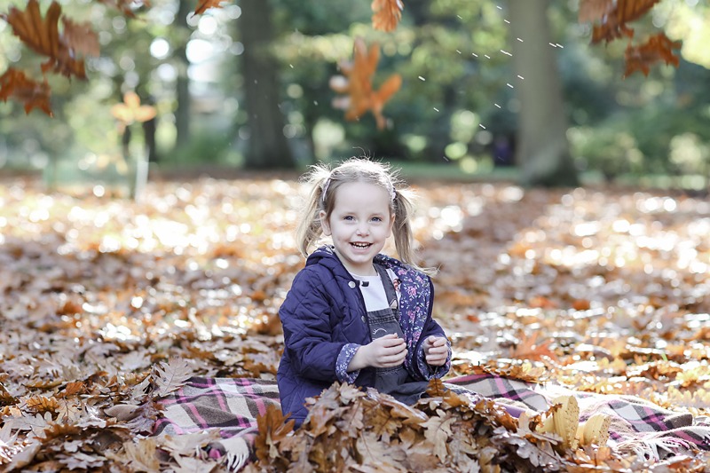 little girl sitting in the autumn leaves