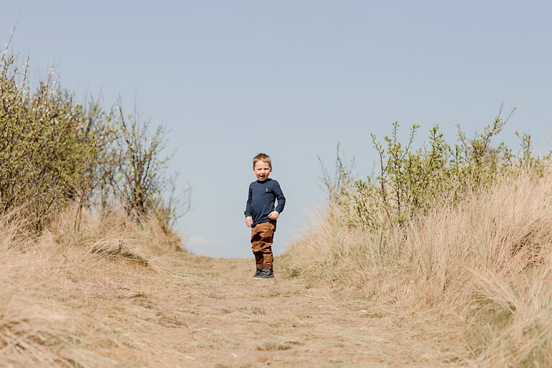 little boy on a sand dune with blue sky