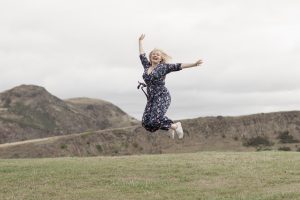 woman jumping in the air with hills behind her